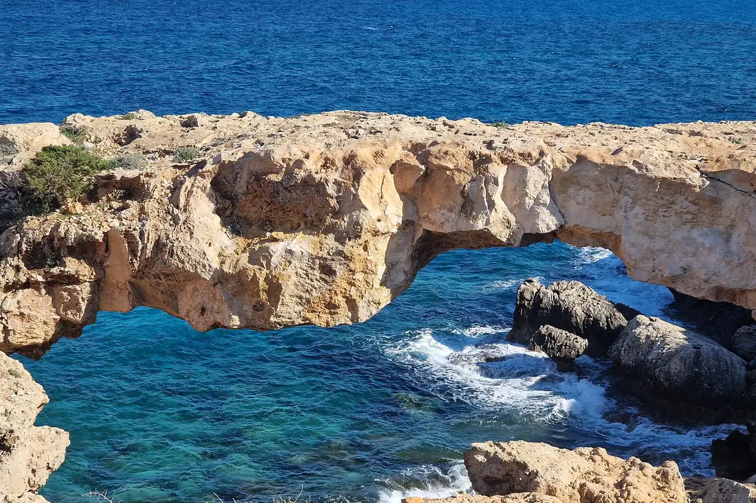 A natural limestone arch above turquoise water on the Cape Greco coast