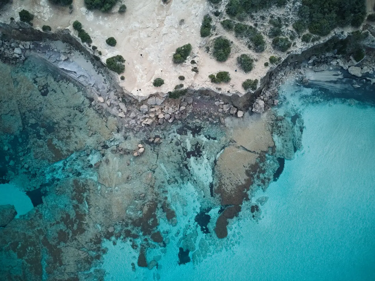 Turquoise shallows and a rocky shore near Neo Chorio, Paphos district, seen from above